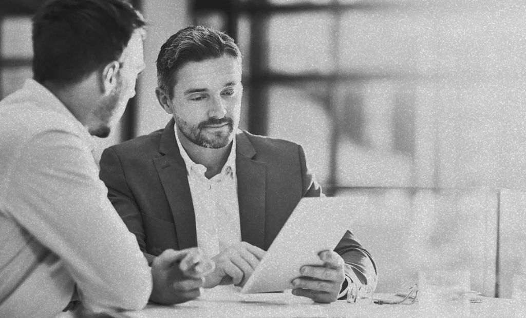 two men sitting looking at an ipad