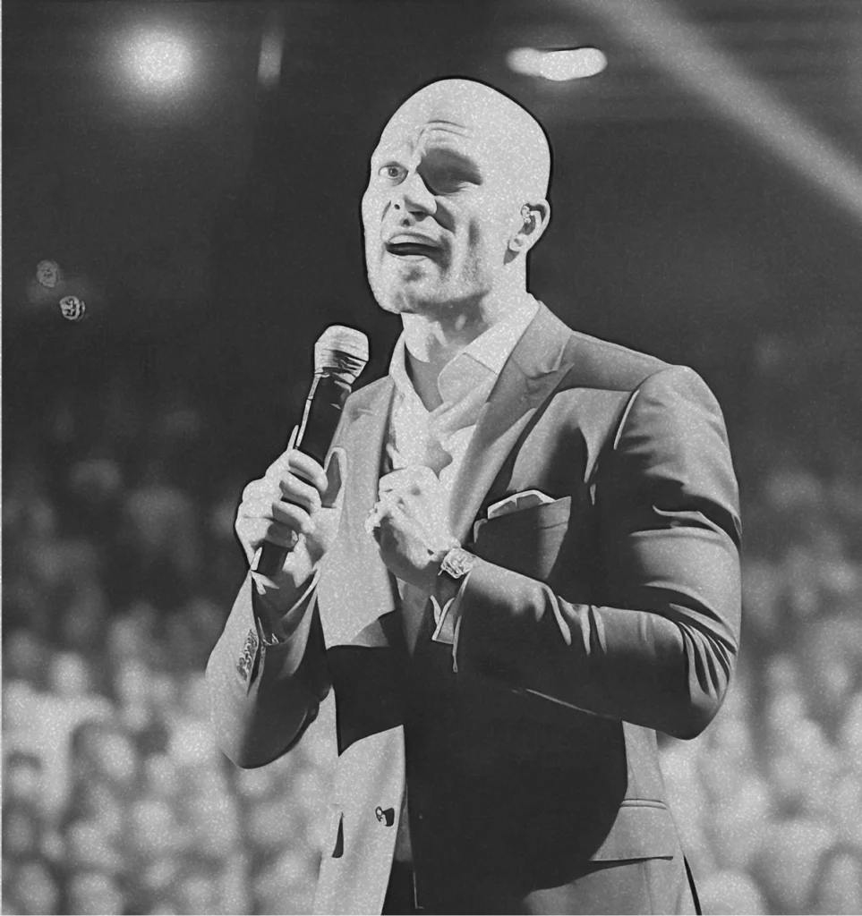 man holding a microphone speaking in front of a crowd of people